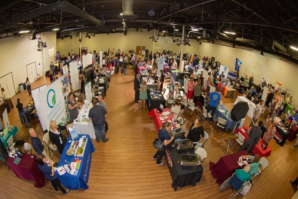 A large group of people are standing around tables at a job fair.