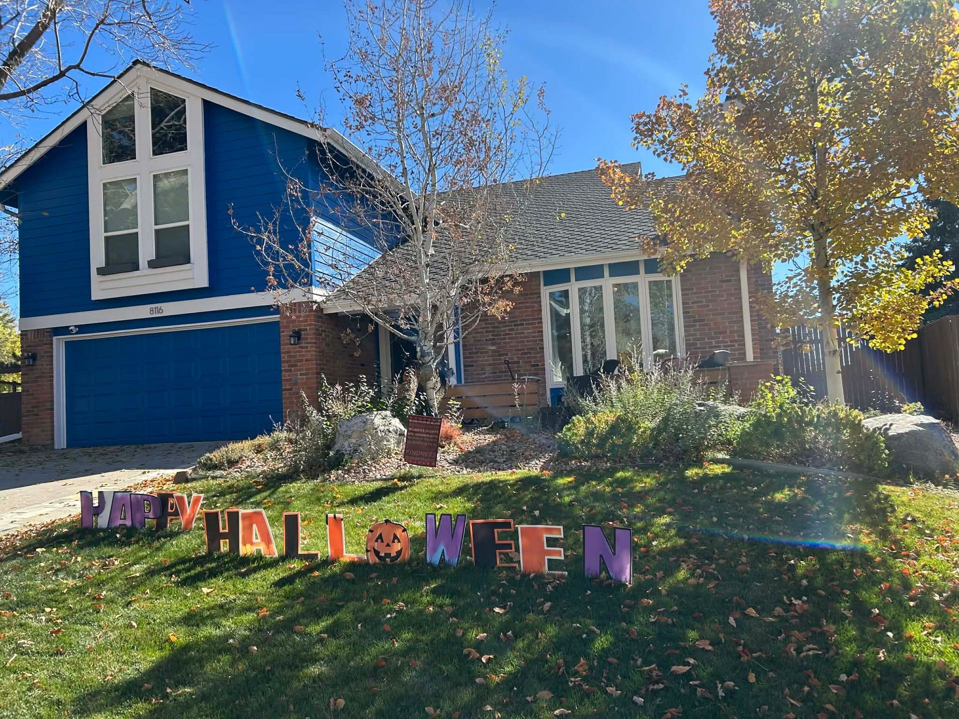 A blue and brick house with a lawn decorated with colorful 