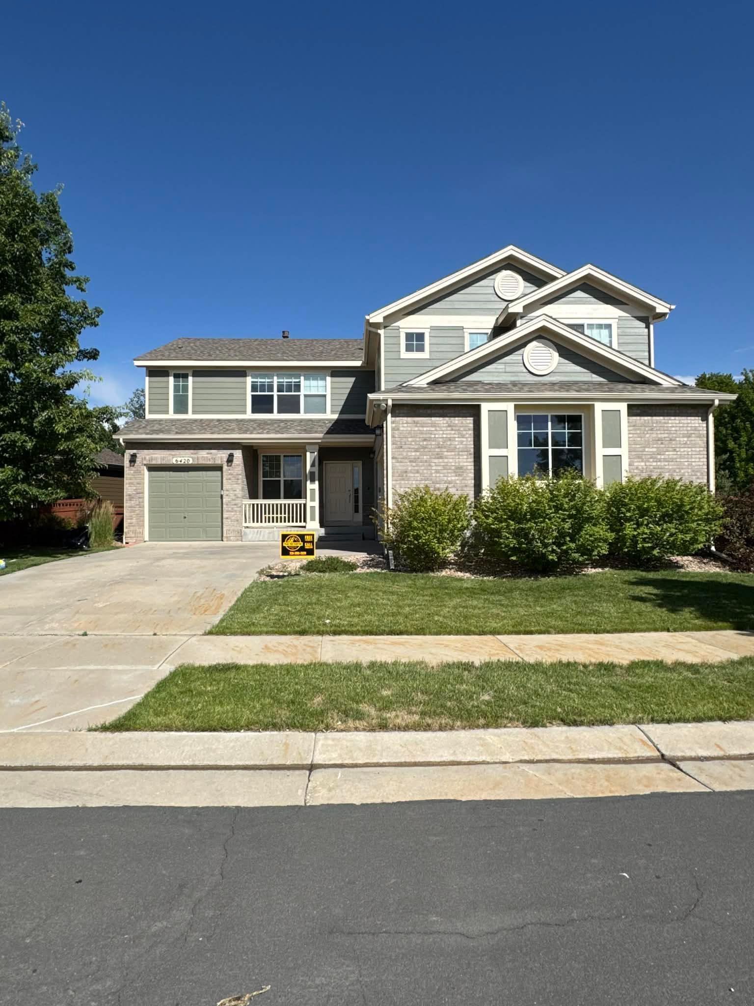 A two-story suburban house with a brick and gray siding facade, a single-car garage, and a manicured front lawn.