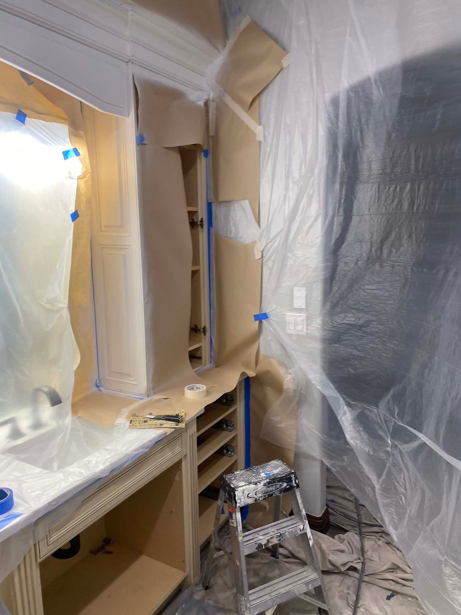 A bathroom vanity under construction, covered in protective brown paper and plastic sheeting, with a small stepladder.