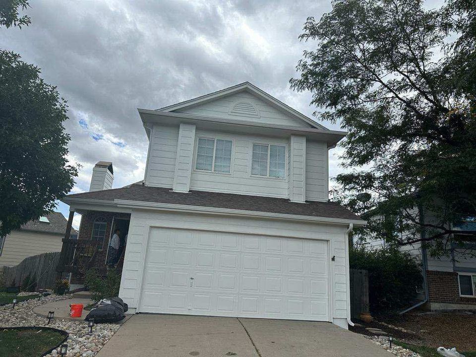 A two-story house with white siding and a large attached garage under a cloudy sky.