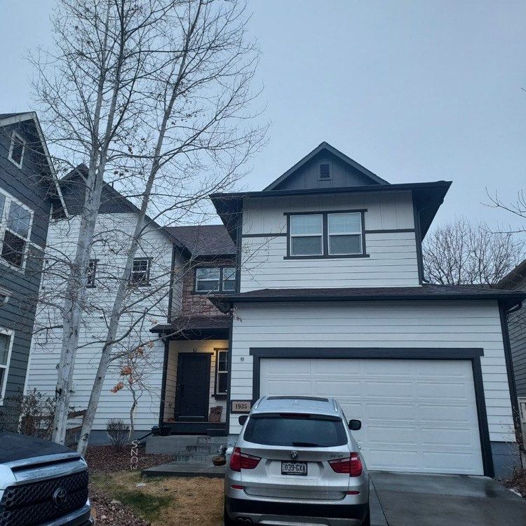 A two-story house with white horizontal siding, dark trim, a gabled roof, and a two-car garage with a silver SUV in front.