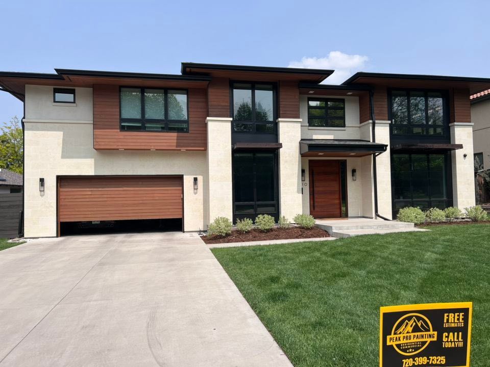 A two-story modern home with wood paneling, cream stone accents, a garage, and a construction sign on the front lawn.