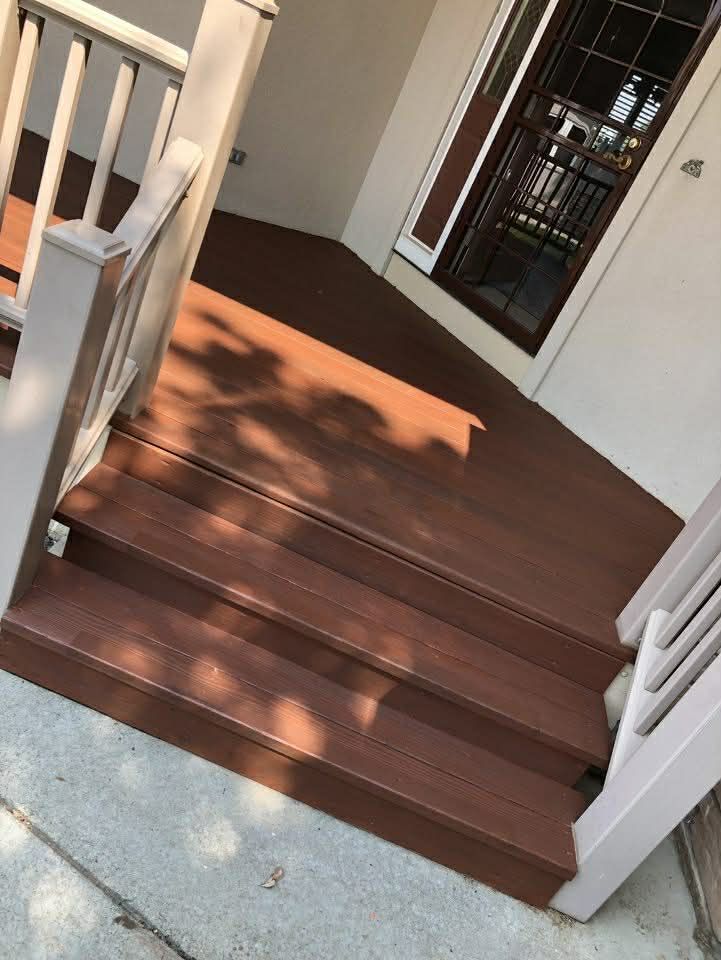 Wooden deck stairs with white railings leading to a doorway.