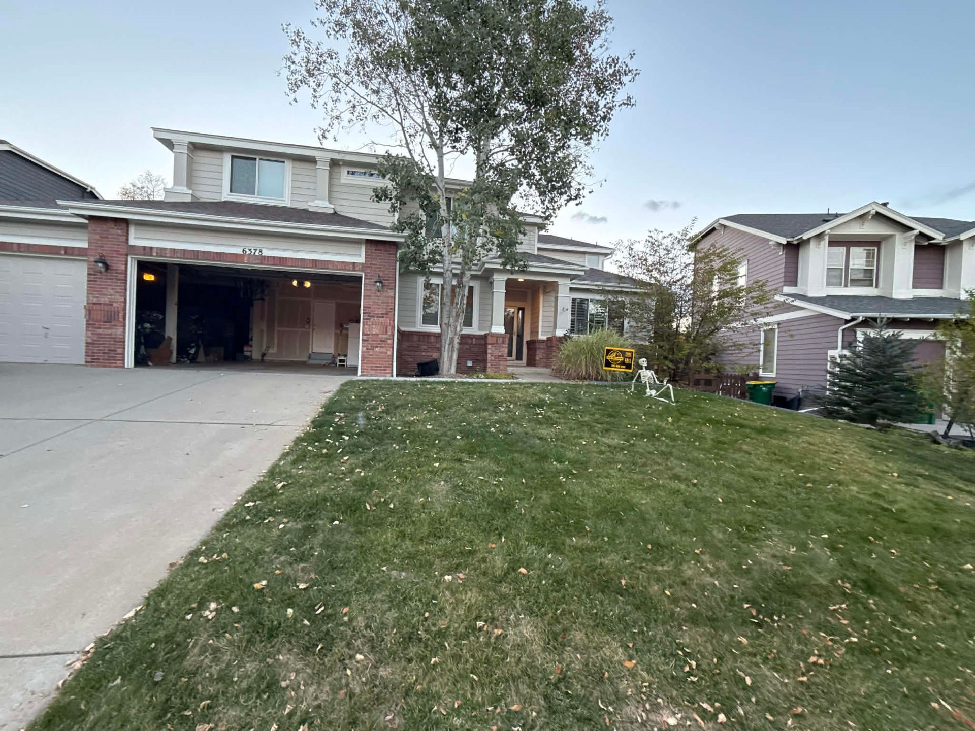 Two neighboring houses under a clear sky, featuring driveways, front yards, and brick accents on the left home.