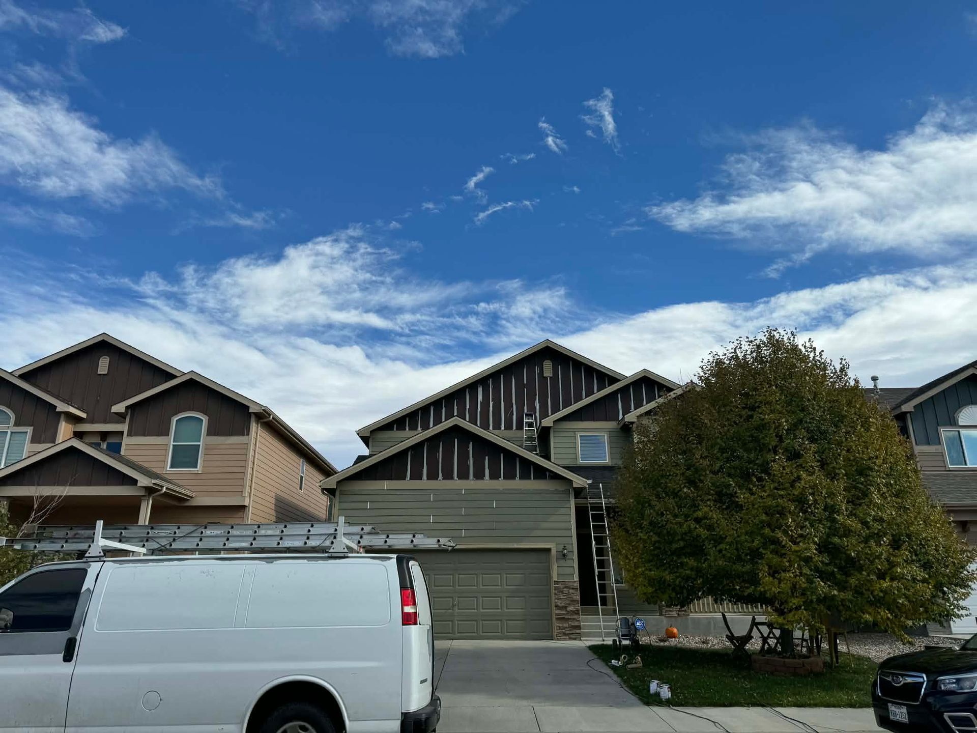 A service van parked in front of a suburban home under a partly cloudy sky.