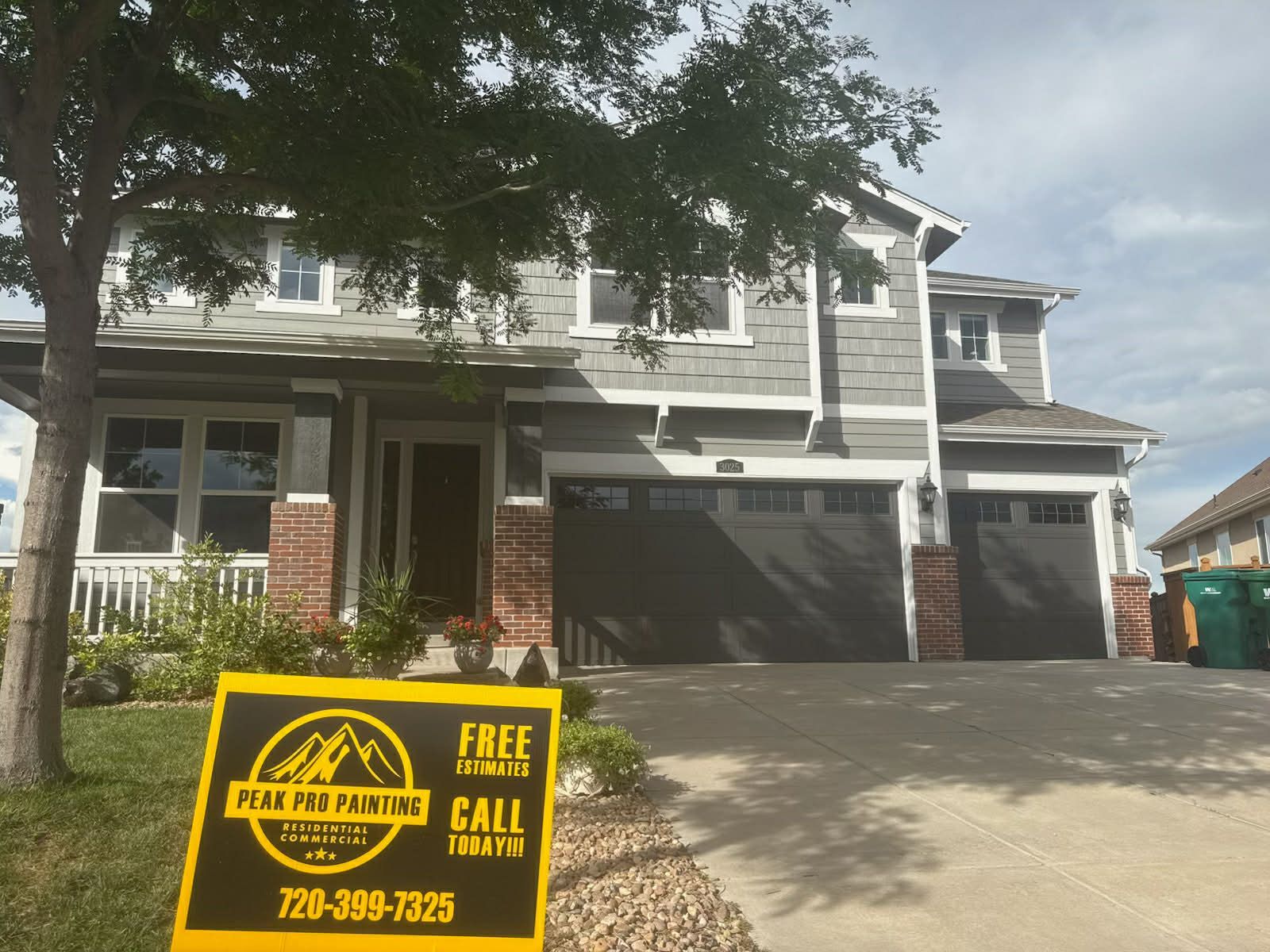 A two-story grey suburban house with a three-car garage and a 