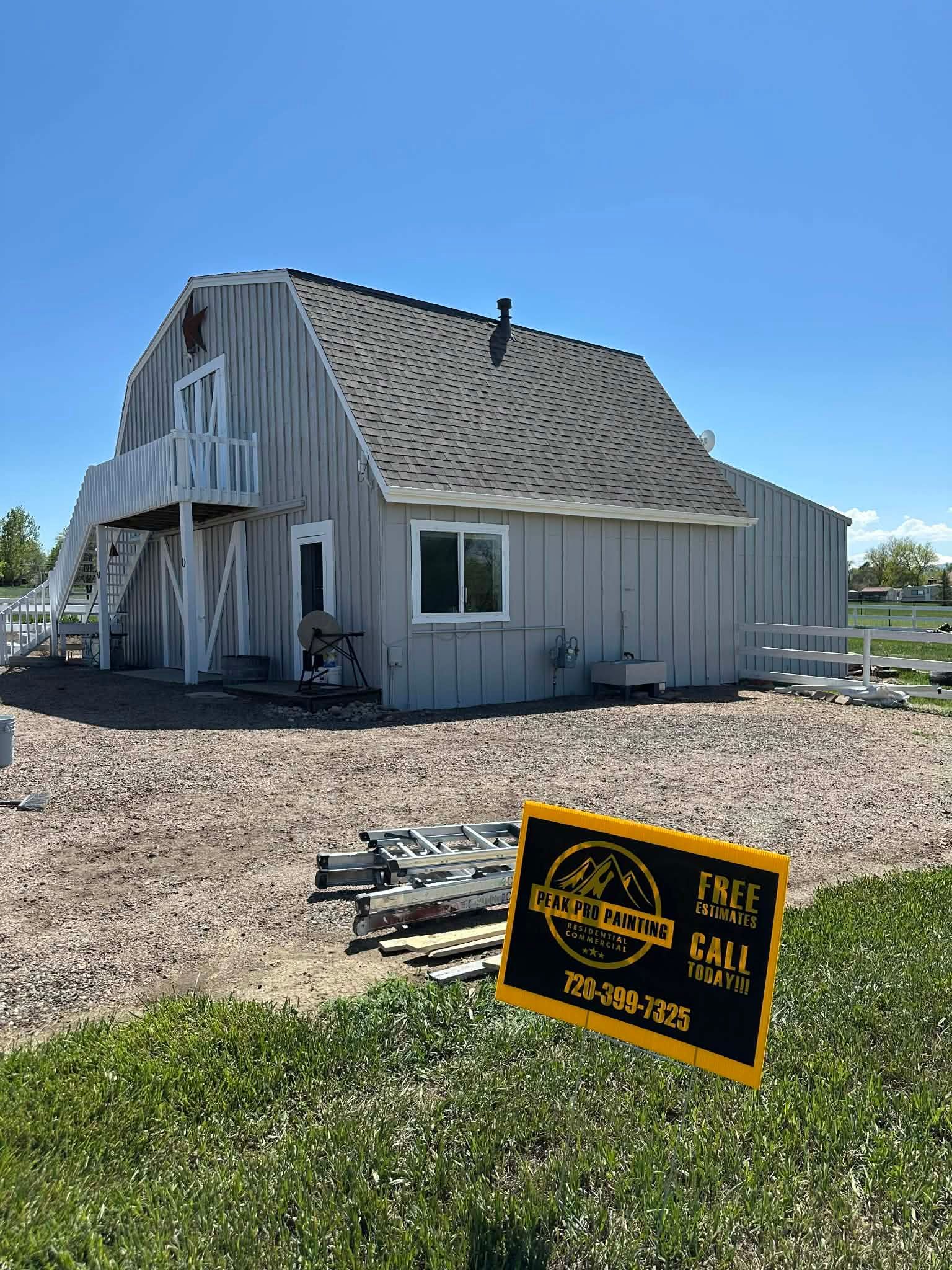 A light gray barn with a balcony and a 