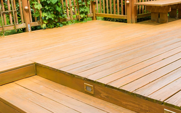 A multi-level wooden deck featuring planks, railings, and a small recessed light on the stair riser.