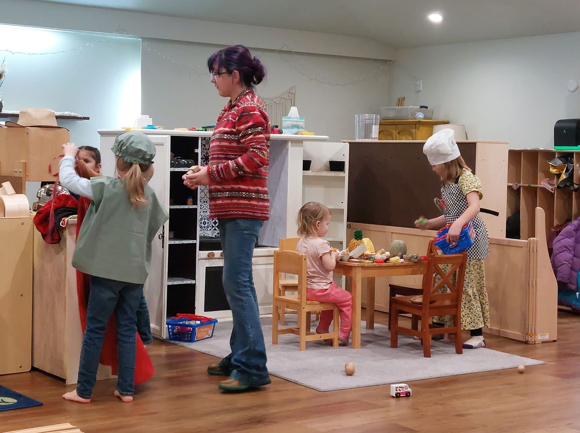 A woman is standing in a room with children playing.