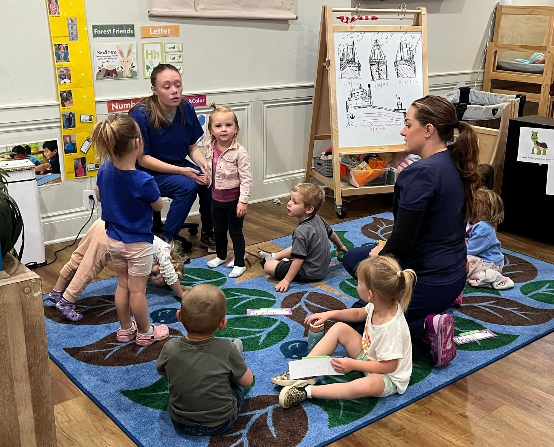 A group of children are sitting on a rug in a circle in a classroom.