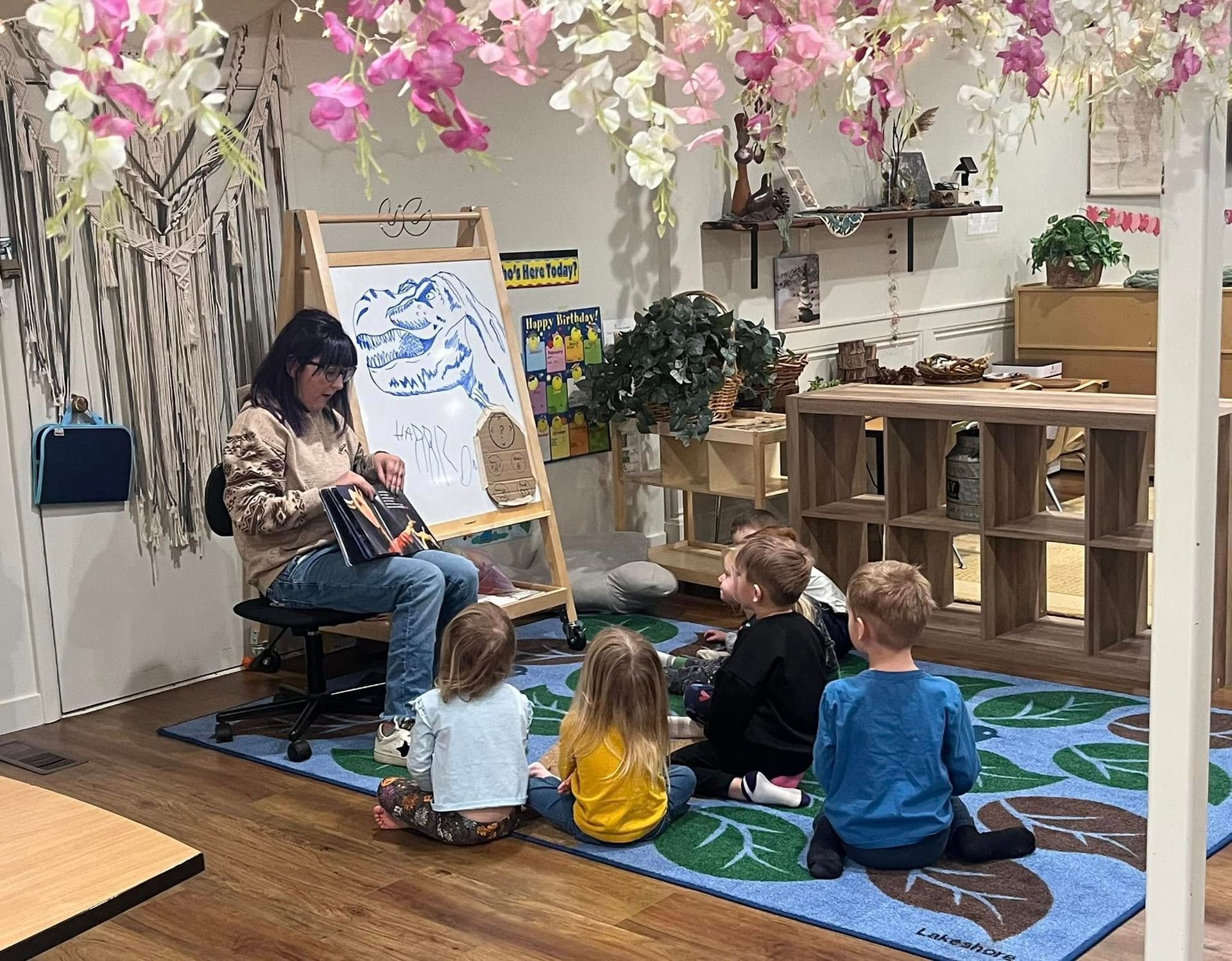 A woman is reading a book to a group of children in a room.