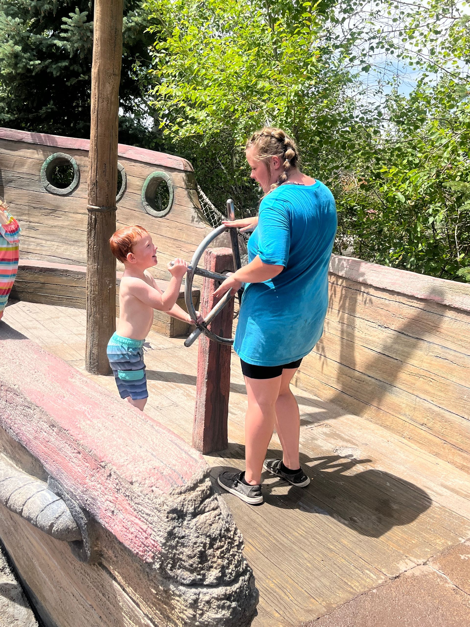 A woman and a boy are playing on a pirate ship.