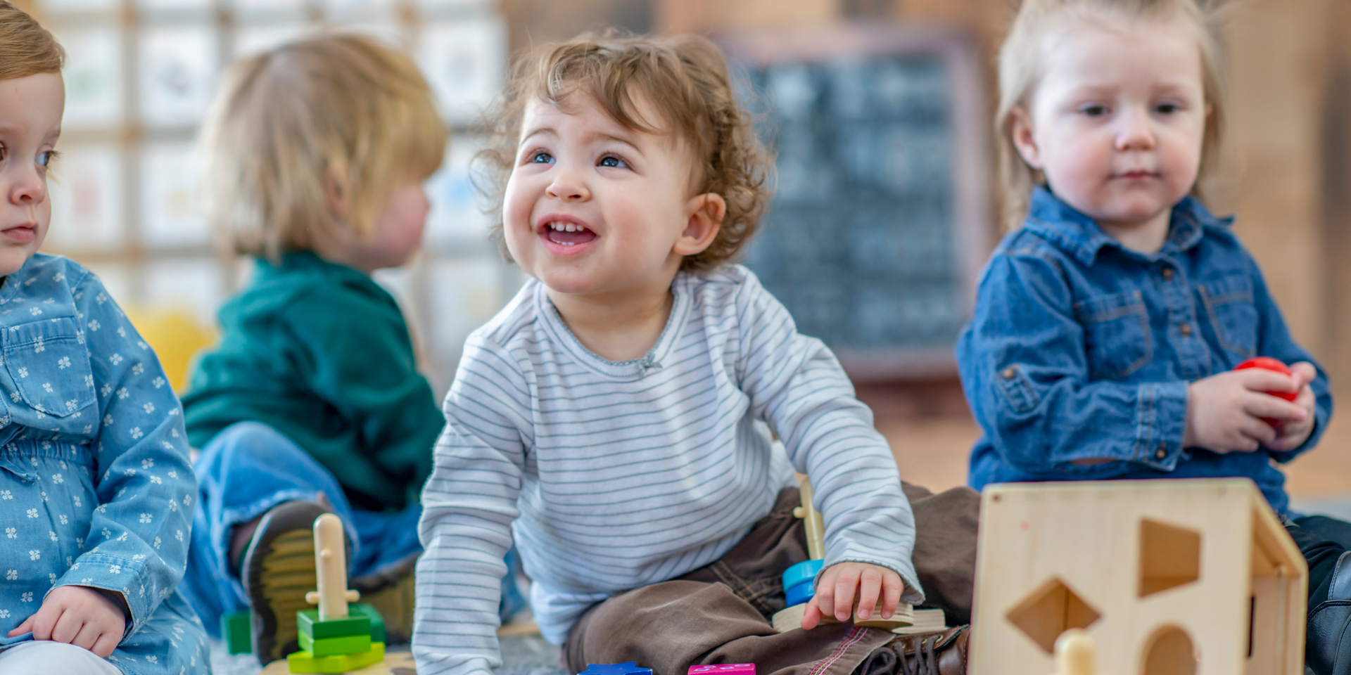 A group of young children are sitting on the floor playing with toys.