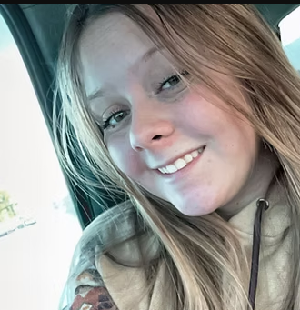 A young woman is smiling while sitting in a car.