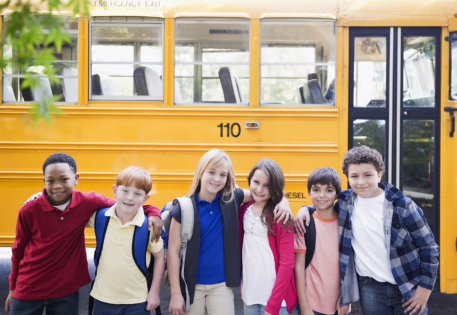 A group of children are posing for a picture in front of a school bus.