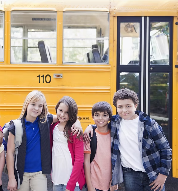 A group of children are posing for a picture in front of a school bus.