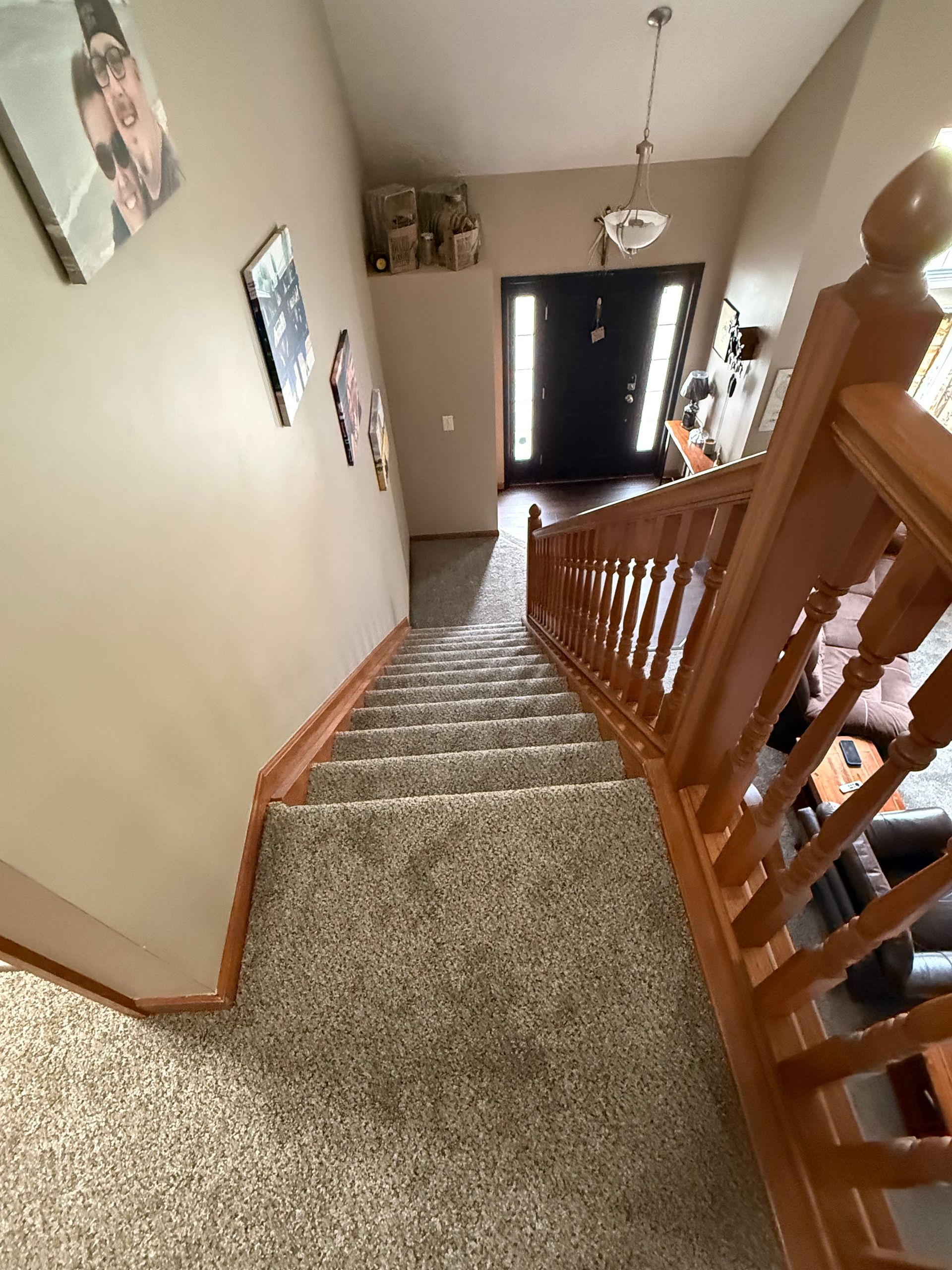 Carpeted indoor staircase with wood banisters and beige walls in a home entryway.