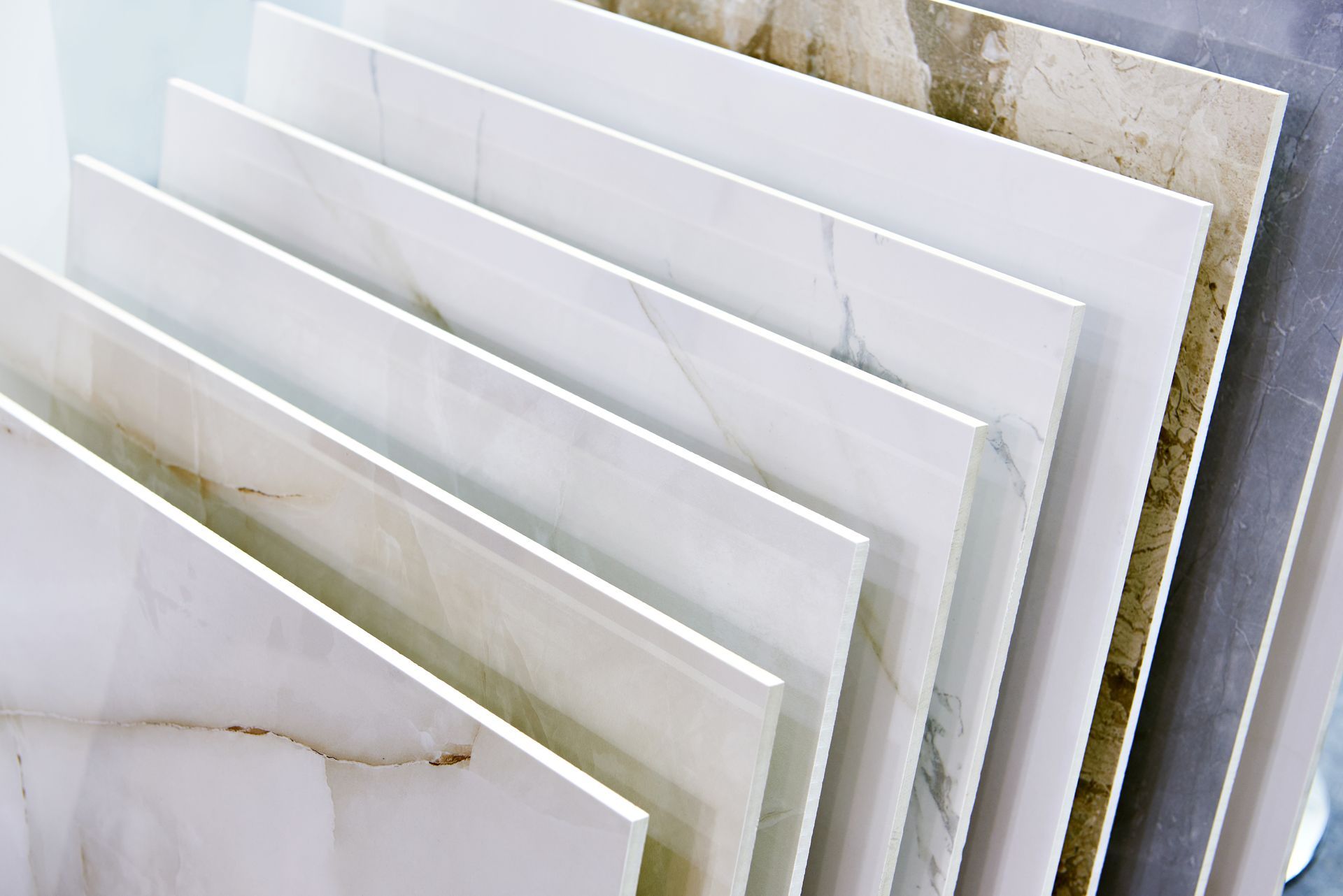 Various ceramic tiles displayed, showcasing different textures and colors, including white, gray, and beige.