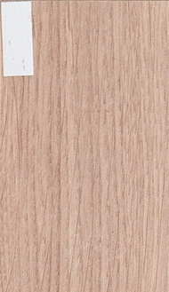 Close-up of light brown wood grain with vertical lines. A small white label is in the upper left corner.