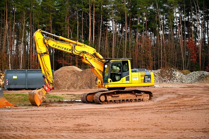 A yellow excavator is digging a hole in a dirt field.