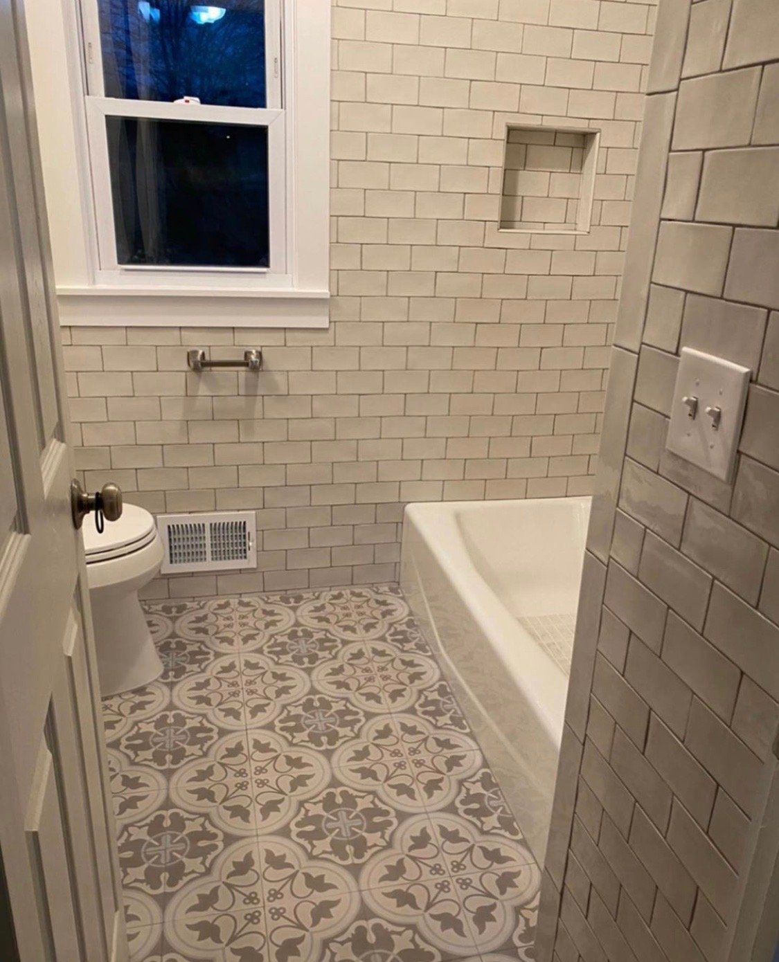 A bathroom with a toilet , tub , and window.