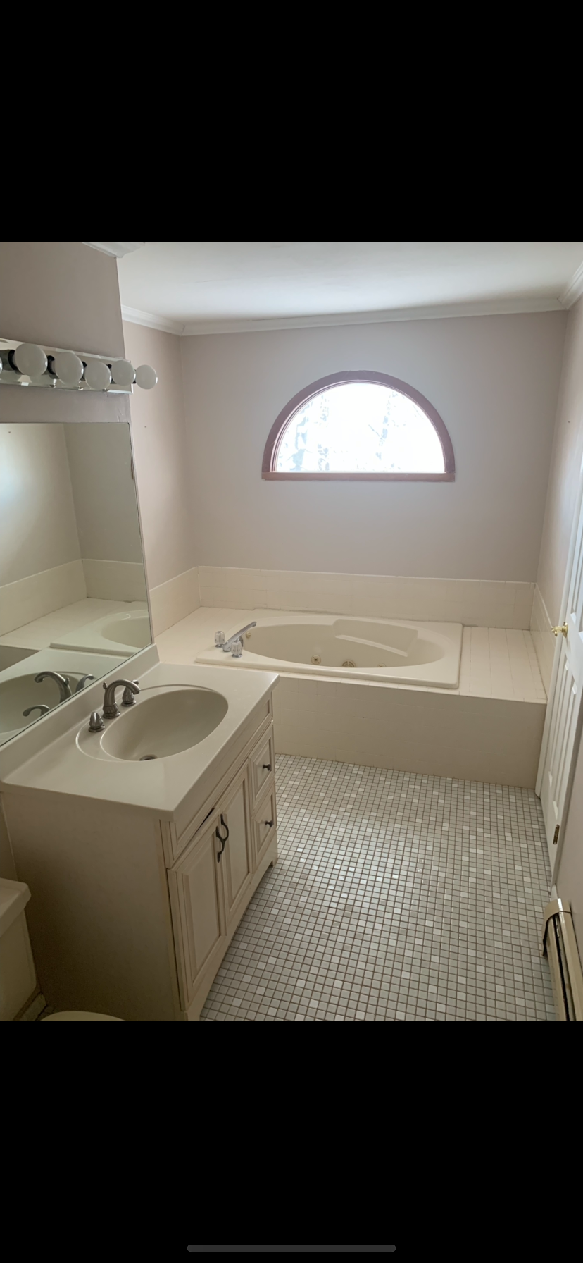 A bathroom with two sinks , a tub , and a window.