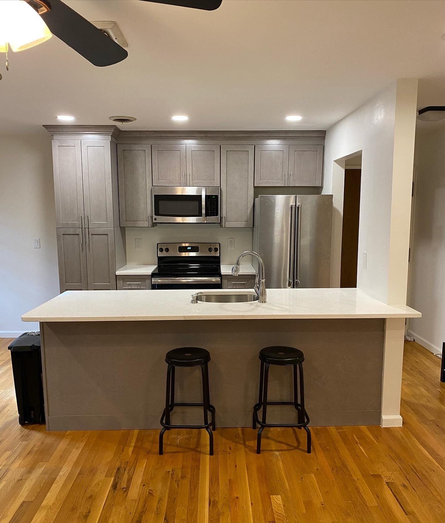 A kitchen with stools and a ceiling fan