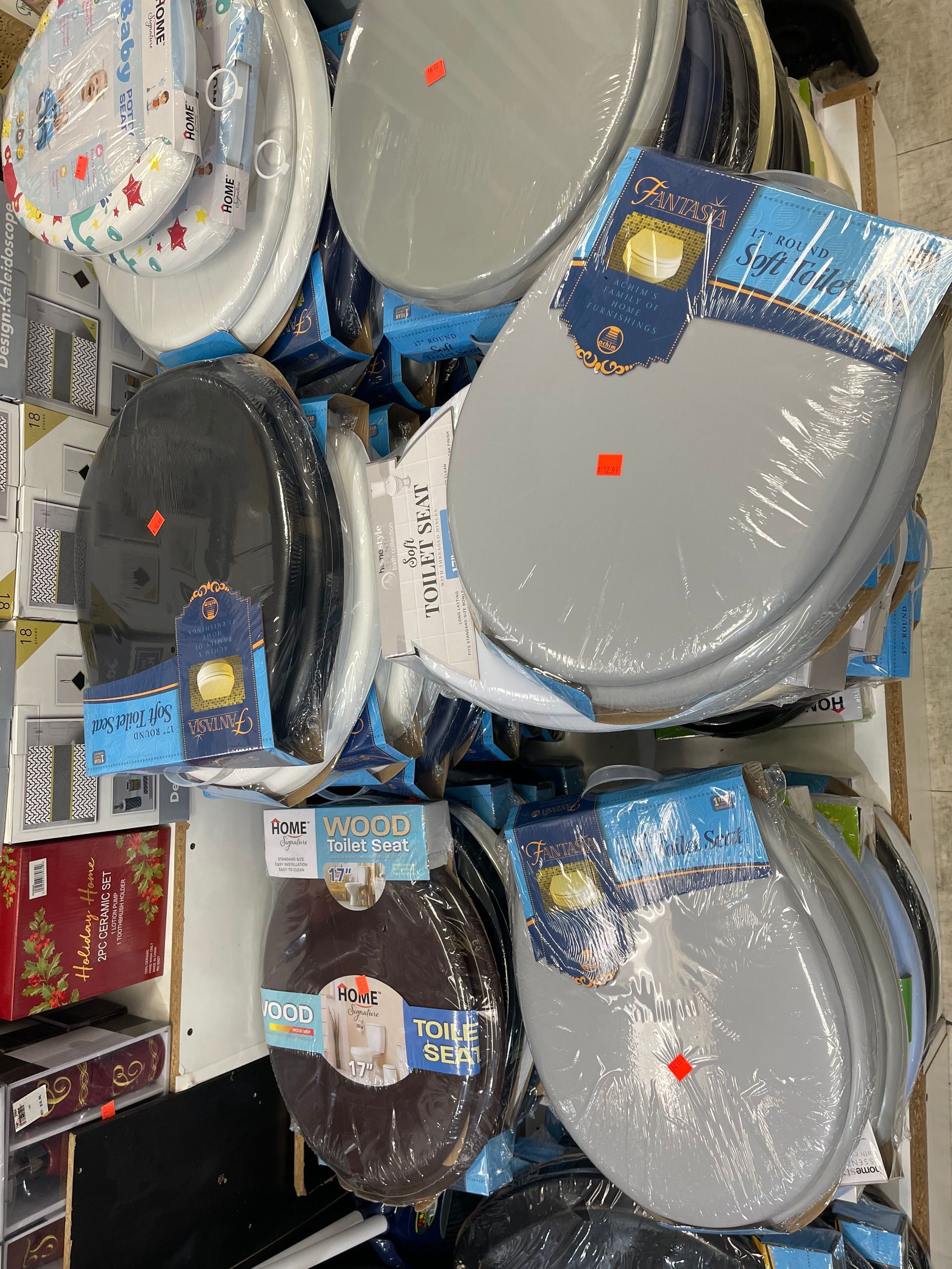 A bunch of toilet seats are stacked on top of each other in a store.