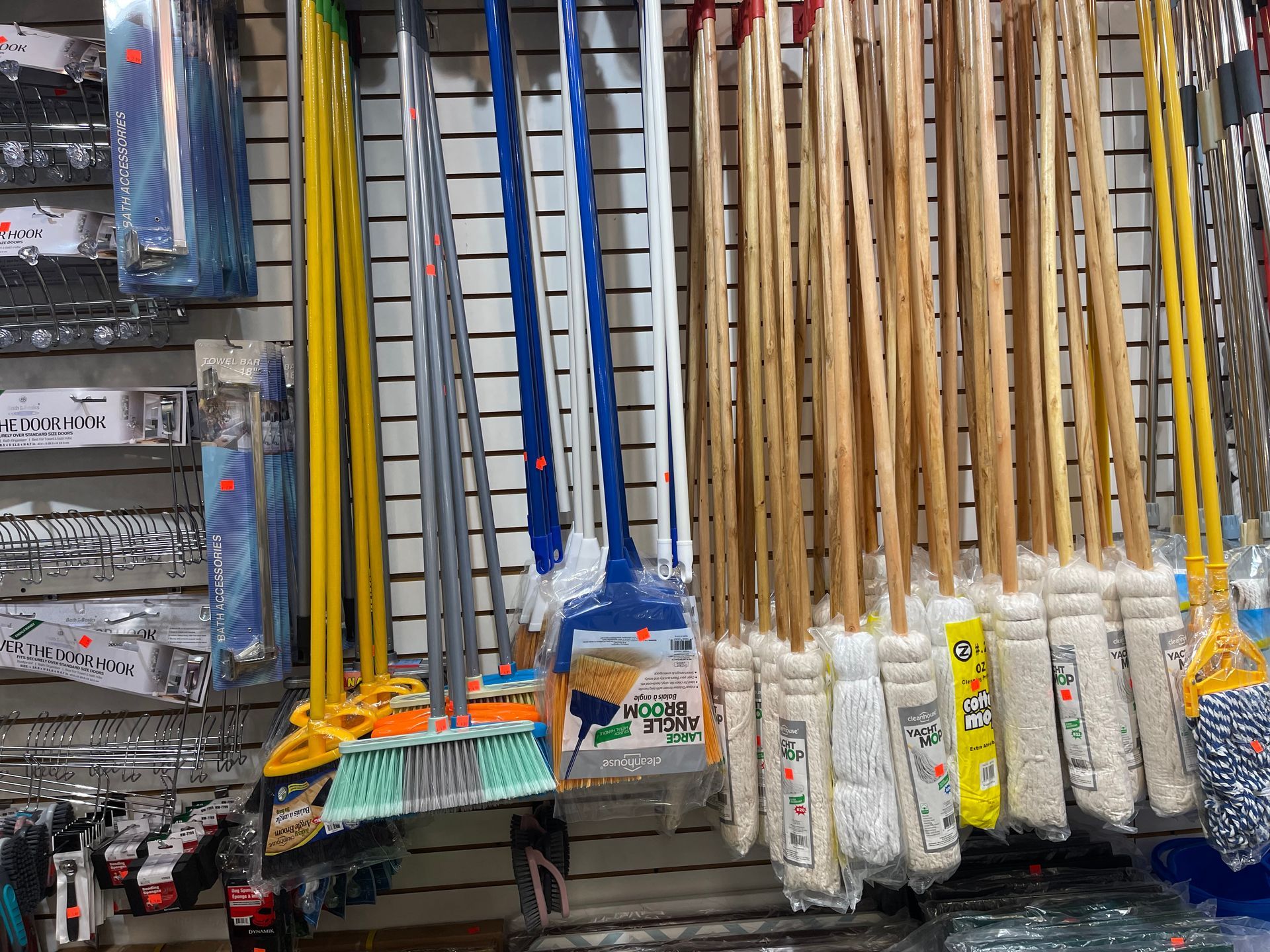 A bunch of mop heads are hanging on a wall in a store.
