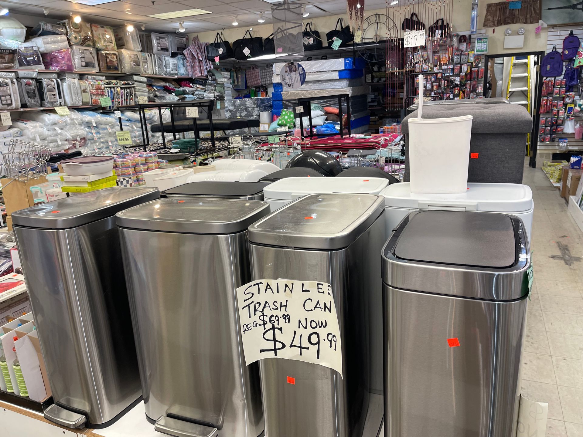 A row of stainless steel trash cans are for sale in a store.