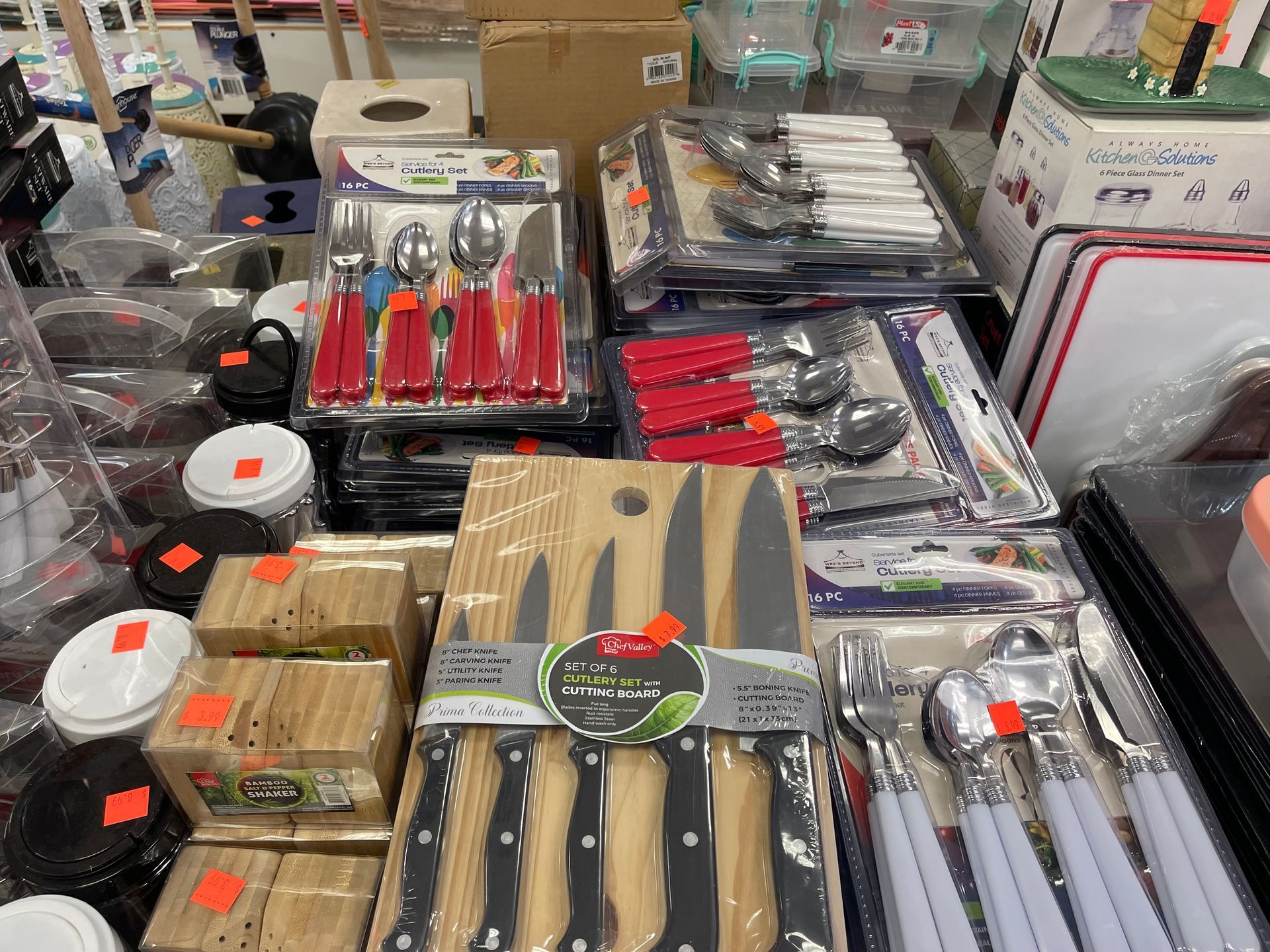 A bunch of knives and silverware are sitting on a table in a store.
