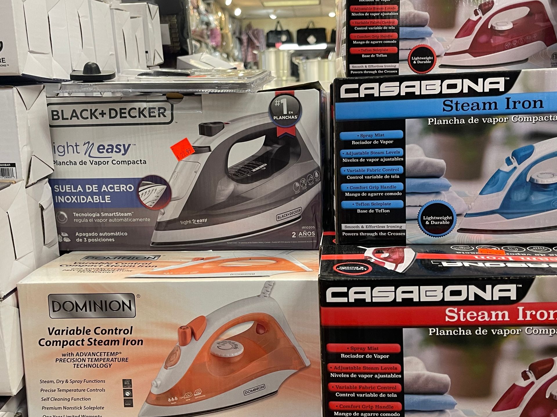 Several boxes of irons are stacked on top of each other in a store.