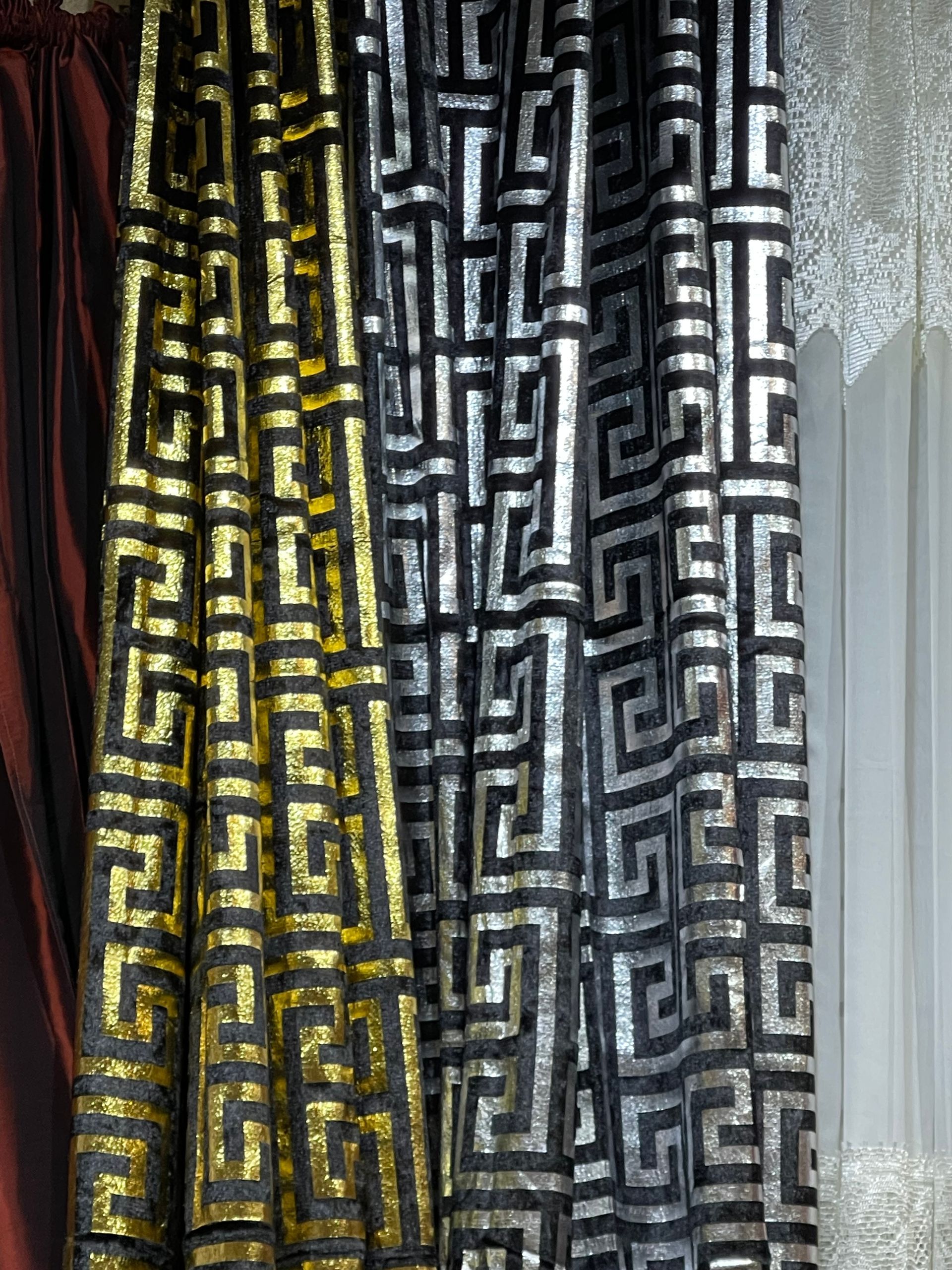 A row of black and gold curtains with a greek key pattern