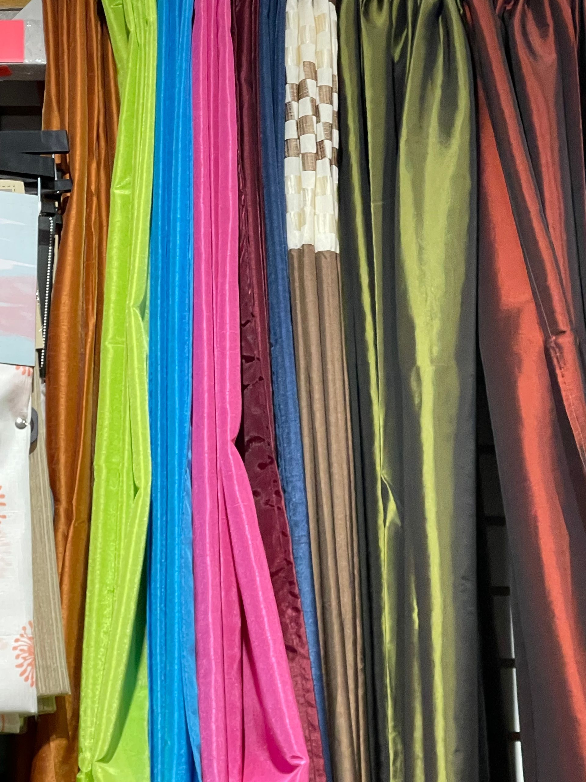 A row of colorful scarves are hanging on a rack