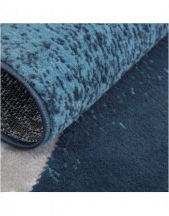 A close up of a blue rug on a white surface.