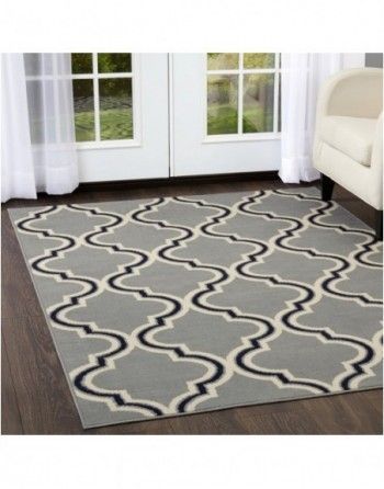 A gray and white rug is sitting on a wooden floor in a living room.