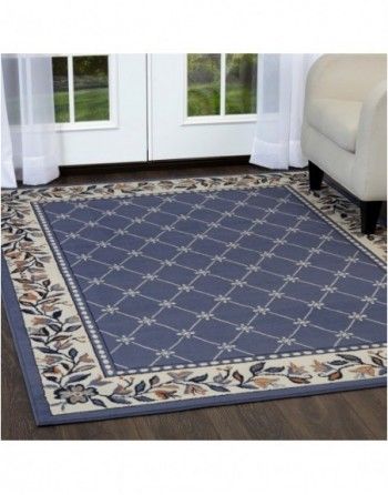 A blue rug with a floral border is on the floor in a living room