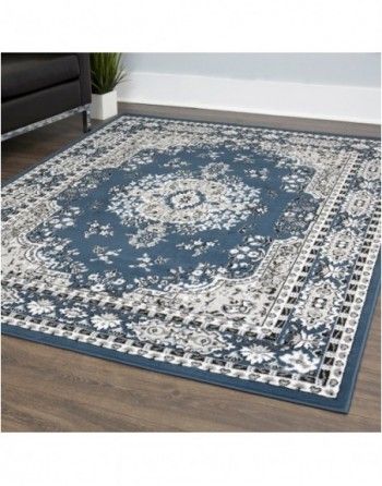 A blue and white rug is sitting on a wooden floor in a living room.