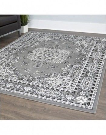 A gray and white rug is sitting on a wooden floor in a living room.