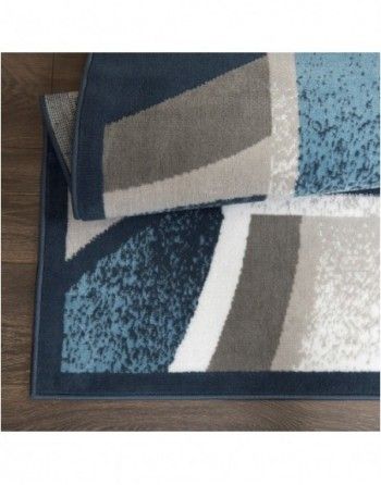 A blue rug with a geometric pattern is laying on a wooden floor.