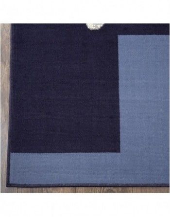 A black rug with a blue border is sitting on a wooden floor.