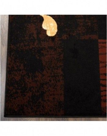 A black and brown rug with a gold leaf on it