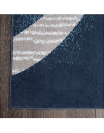 A blue rug with a geometric pattern is on a wooden floor.