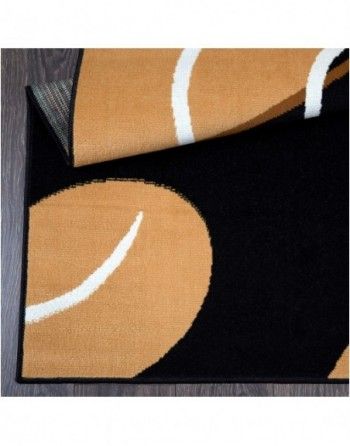 A black and tan rug with a white stripe on the bottom is on a wooden floor.