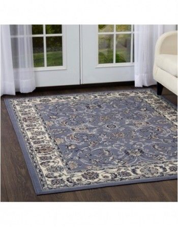 A blue rug is sitting on a wooden floor in a living room next to a couch.