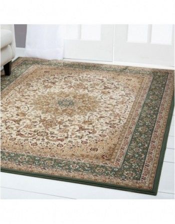 A rug with a green border is on the floor in a living room.