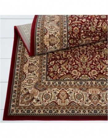 A red and gold rug is laying on a white table.