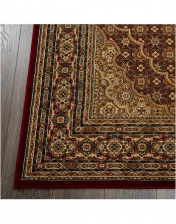 A red and gold rug is on a wooden floor.