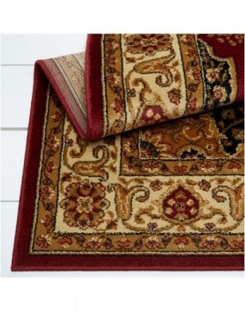 A rug with a red border is on a white surface